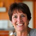 Portrait of Lisa, a 48-year-old chef and mother, smiling brightly in a warm, inviting kitchen.