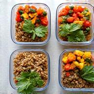 A clean, modern kitchen island with portioned meal prep containers filled with colorful, plant-based food, emphasizing efficiency.