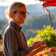 A person happily selecting fresh ingredients at a Boulder farmer's market, representing thoughtful, local plant-based choices.