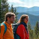 Diverse group of friends hiking a mountain trail at sunset, laughing.