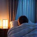 Person sleeping peacefully in a comfortable bed, surrounded by soft lighting.